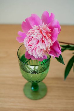 Cam pembe vazoda bir buket şakayık, yeşil bir bardak su, yatağın üzerinde mumlar. Yatak odası..