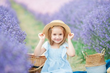 Mavi elbiseli, kahverengi gözlü, 5 yaşında şirin bir kızın portresi. Lavanta tarlasında mutlu bir çocuk.