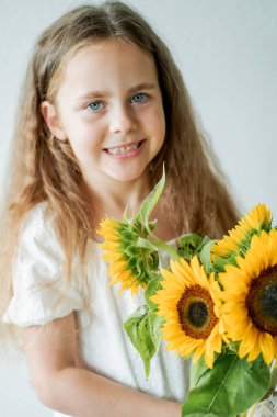 Evinde bir buket ayçiçeğiyle mavi gözlü tatlı kıvırcık kız portresi.