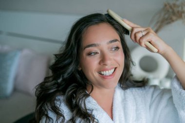 Genç ve güzel bir kadın uzun saçlarını ahşap bir tarakla tarıyor..