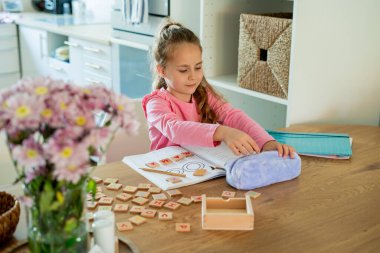 6 yaşında tatlı bir kız. Evde, masada, mutfakta ödev yapıyor. Okula dönelim. Eğitici oyunlar. Samimi.