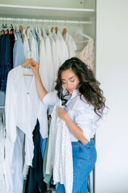 Genç, siyah saçlı, kıvırcık saçlı güzel kadın geniş dolapta bir şeyler düzenliyor. Ev organizasyonu. Bir şeyler yıkıyorum..