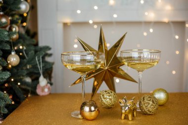 Noel dekoru. Altın zemin üzerinde şampanya olan güzel cam bardaklar. Noel ağacı.