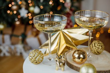 Noel dekoru. Altın zemin üzerinde şampanya olan güzel cam bardaklar. Noel ağacı.