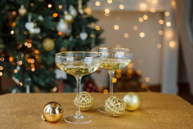Noel dekoru. Altın zemin üzerinde şampanya olan güzel cam bardaklar. Noel ağacı.