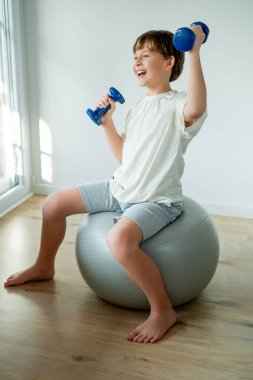 Sevimli 10 yaşındaki çocuk evde halterli ve spor yapıyor. Evde eğitim.