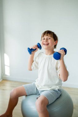 Sevimli 10 yaşındaki çocuk evde halterli ve spor yapıyor. Evde eğitim.