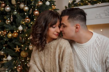 Aile Noel ağacının yanında oturuyor ve hediyeleri açıyor. Kış tatili Tatiller