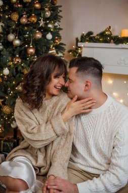 Aile Noel ağacının yanında oturuyor ve hediyeleri açıyor. Kış tatili Tatiller