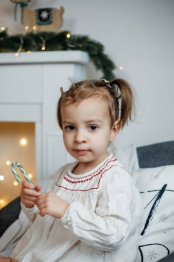 Küçük kız Noel ağacının yanında oturuyor ve hediyeleri açıyor. Kış tatili.