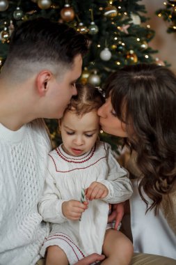 Aile Noel ağacının yanında oturuyor ve hediyeleri açıyor. Kış tatili Tatiller