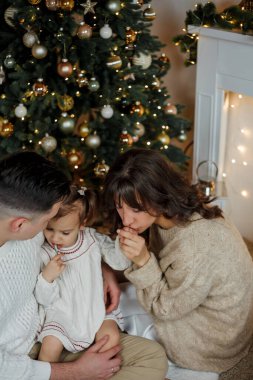 Aile Noel ağacının yanında oturuyor ve hediyeleri açıyor. Kış tatili Tatiller