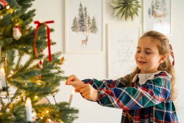 Evdeki Noel ağacını süsleyen tatlı mutlu küçük kız. Kış tatili Samimi.