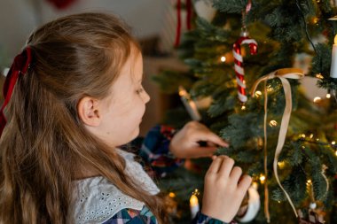 Evdeki Noel ağacını süsleyen tatlı mutlu küçük kız. Kış tatili Samimi.