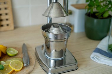 Bej ışıklı mutfakta ev yapımı limonata yapıyorum. Tahtada limon ve limon, kavanozda nane şekeri. Meyve sıkacağı.