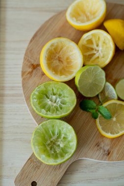 Bej ışıklı mutfakta ev yapımı limonata yapıyorum. Tahtada limon ve limon, kavanozda nane şekeri. Meyve sıkacağı.