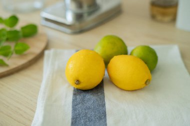 Bej ışıklı mutfakta ev yapımı limonata yapıyorum. Tahtada limon ve limon, kavanozda nane şekeri. Meyve sıkacağı.