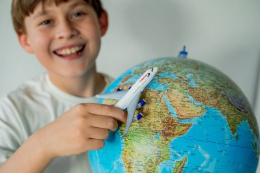 Küçük şirin çocuk elinde küçük bir uçakla dünyaya bakıyor. Yolculuk için rota hazırlanıyor. Ülke seçiliyor.