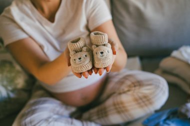 Pijamalı güzel bir kadın doğum koğuşu için bebek eşyalarıyla dolu bir çanta hazırlıyor. Göbekli manken anne olmaya hazırlanıyor..