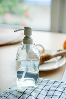 Lavabonun yanında bulaşık yıkamak için bir ekofırça, cam şişede deterjan ve havlu. Parlak mutfak iç mimarisi.