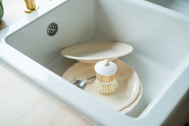 Kirli bulaşıklar lavaboda. Eko-bulaşık fırçası. Parlak mutfak iç mimarisi.