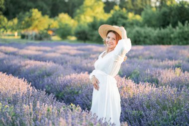 Güzel bir kadın lavanta tarlasında yaz esintisinin tadını çıkarıyor. Güneş ışığındaki sarışının portresi.