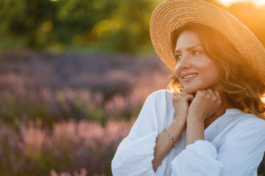 Güzel bir kadın lavanta tarlasında yaz esintisinin tadını çıkarıyor. Güneş ışığındaki sarışının portresi.
