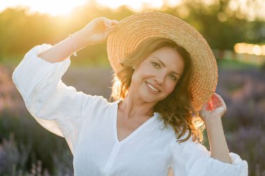 Güzel bir kadın lavanta tarlasında yaz esintisinin tadını çıkarıyor. Güneş ışığındaki sarışının portresi.