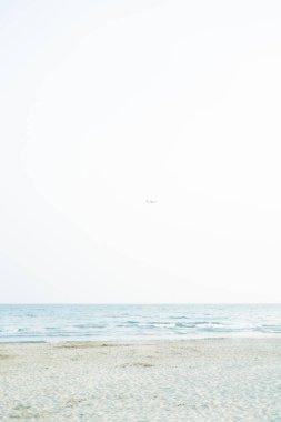 Gün batımında denize yakın. Kumsalda kum var. Mavi su.