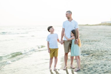 Baba ve kızı deniz kenarında. Kumsalda kum var. Mavi su. seyahat.