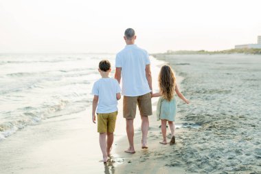 Baba ve kızı deniz kenarında. Kumsalda kum var. Mavi su. seyahat.