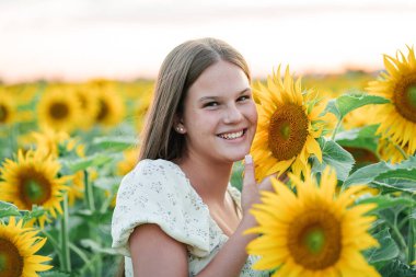 Ayçiçeği tarlasında gülümseyen genç kız.
