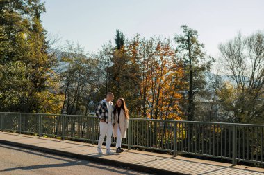 Birbirine aşık genç bir çift Sonbahar şehrinde nehir kenarında bir köprüde.