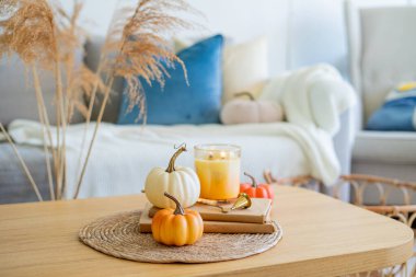 Sıcak güneş gözlükleriyle evde sonbahar dekoru. Balkabağı, mum, kurumuş çiçekler, yastıklar. Samimi.