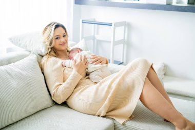 Genç anne yeni doğmuş bebeği şefkatle kucağında tutuyor. sağlıklı annelik.