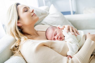 Genç anne yeni doğmuş bebeği şefkatle kucağında tutuyor. sağlıklı annelik.