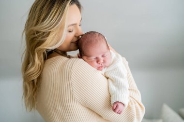 Genç anne yeni doğmuş bebeği şefkatle kucağında tutuyor. sağlıklı annelik.