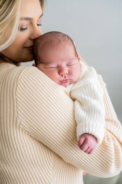 Genç anne yeni doğmuş bebeği şefkatle kucağında tutuyor. sağlıklı annelik.