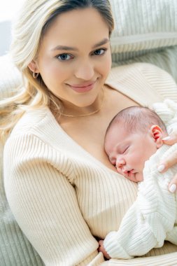 Genç anne yeni doğmuş bebeği şefkatle kucağında tutuyor. sağlıklı annelik.