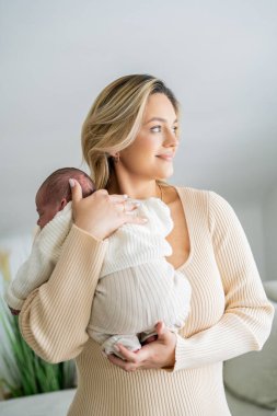 Genç anne yeni doğmuş bebeği şefkatle kucağında tutuyor. sağlıklı annelik.