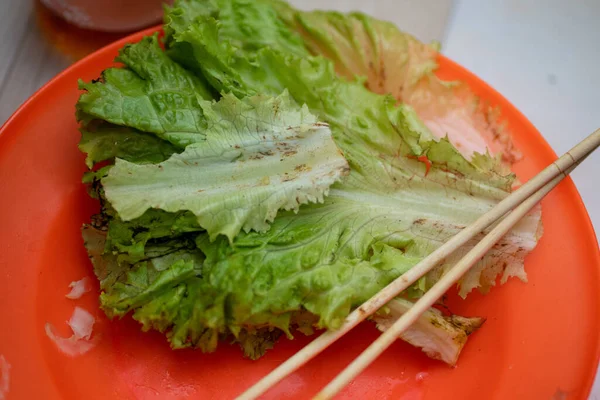 Green Lettuce Sheets on Plastic Plate with Wooden Chopsticks Close Up