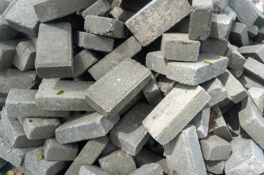 Pile of gray concrete bricks in the middle of a city park construction close up