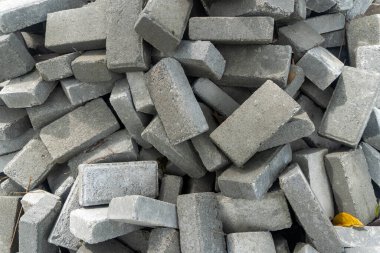 Pile of gray concrete bricks in the middle of a city park construction close up