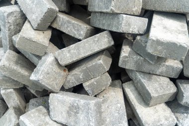 Pile of gray concrete bricks in the middle of a city park construction close up