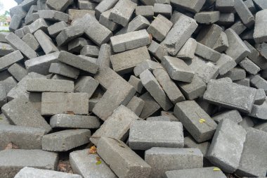 Pile of gray concrete bricks in the middle of a city park construction close up