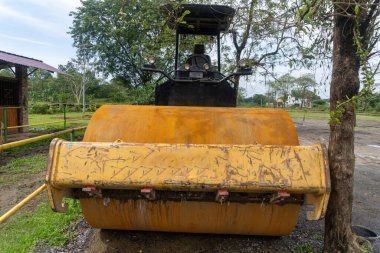 Yellow drum roller machine vehicle parking in the middle of city park landscape