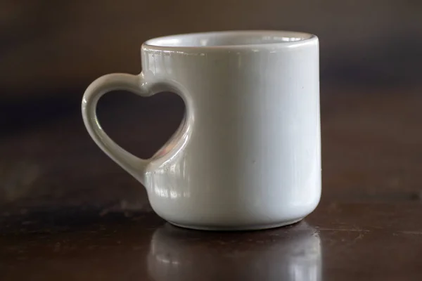 Love in the Morning: A White Mug with Heart Shaped Handle on Wooden Table close up