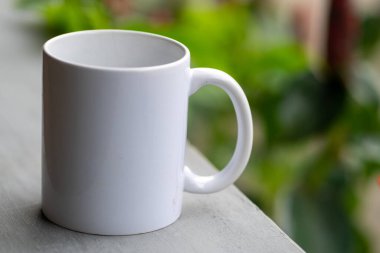 Bulanık arkaplanı olan beyaz seramik kahve kupası.