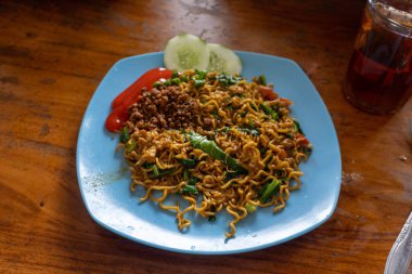Indonesian Popular Instant fried Noodle. Served with Scrambled Egg, Tomato, Cucumber, letuce, and chilli