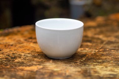 White mug, mock up, empty space for artwork, text, standing on stone, outdoors, green grass, trees, sky in the background, soft sunlight, nature